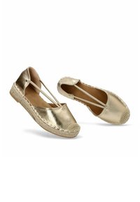 Bailarinas metálicas doradas con suelas de yute trenzado y tiras elásticas. Presentan punta redondeada y detalles de costura alrededor del borde.