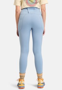 Ljust blå leggings gjorda av elastiskt material, designade med hög midja, smickrande passform och bakfickor. Kompletteras med färgglada skor och strumpor.