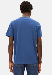 T-shirt bleu à manches courtes en coton doux, présentant une coupe décontractée et un col rond. Associé à un jean en denim.