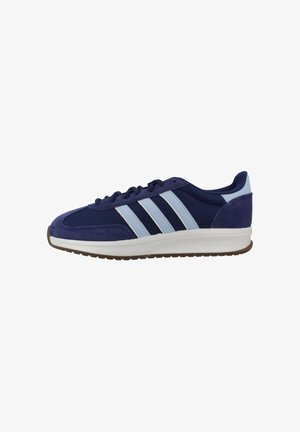 Zapatilla deportiva azul marino con rayas azul claro, suela blanca, parte superior de malla texturizada y ante, y suela exterior marrón con dibujo.