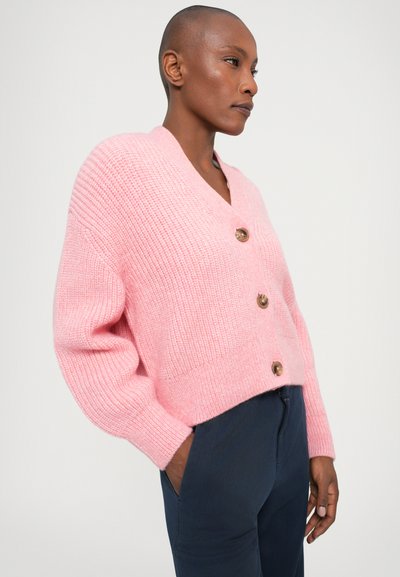 Short pink knitted cardigan with a V-neck, long sleeves, and three wooden buttons down the front. Cropped design with a textured finish.