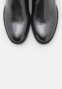 Stivali alla caviglia neri lucidi con finitura liscia, punta arrotondata e parte superiore testurizzata, dotati di suola bassa e piatta e dettagli cuciti.