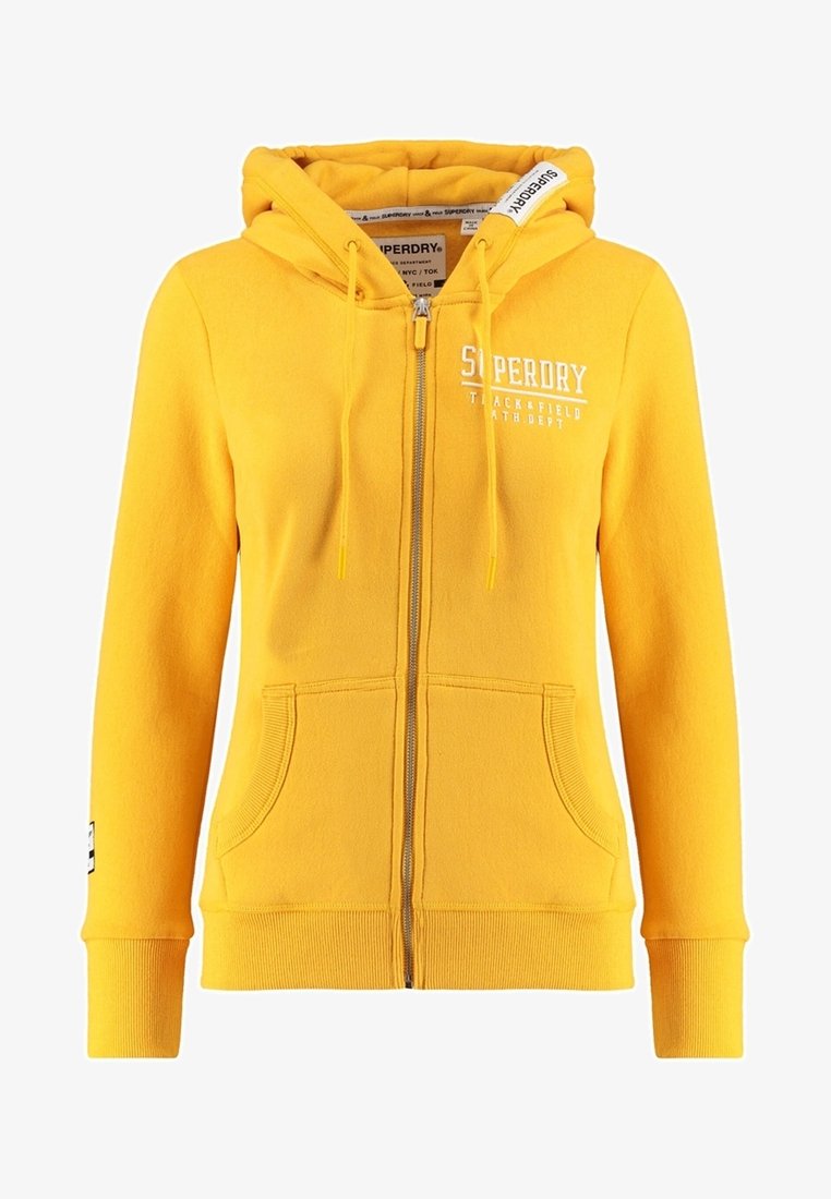 Sweat à capuche jaune zippé avec poches avant, capuche avec cordon de serrage et logo blanc "Superdry Track & Field Ath. Dept" sur la poitrine et l'étiquette de la capuche.