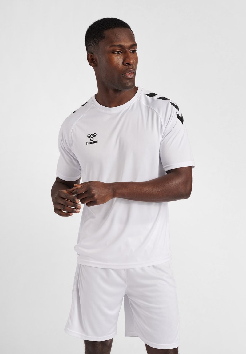 T-shirt et shorts de sport blancs en matériau léger ; présentent un logo Hummel noir et des accents en chevrons noirs sur l'épaule.