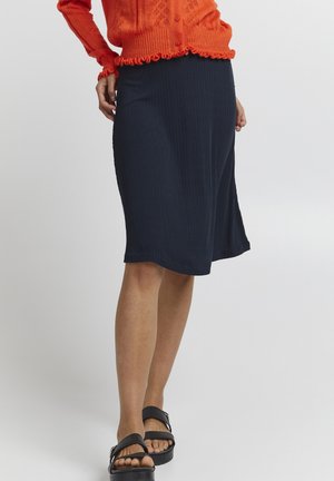 Laivastonsininen ribbihame, jonka pituus on polveen ja lievästi levenevä helma. Yhdistetty mustiin tasapohjaisiin sandaaleihin. Kankaan pinta on teksturoitu, jossa on pystysuorat viivat.