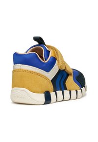 Zapatilla deportiva infantil en azul, amarillo y negro. Presenta materiales de ante y malla, correa de velcro, cuello acolchado y suela de goma texturizada.