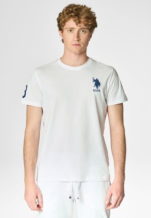 T-shirt bianco in cotone con scollatura rotonda, caratterizzato da un logo USPA blu navy sul lato sinistro del petto e un numero sulla manica. Maniche corte.