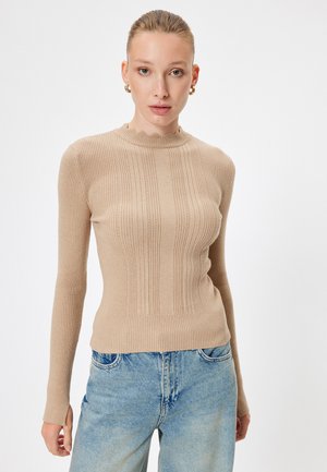 Pull en tricot côtelé beige avec des manches longues, un col montant et des bords festonnés. Présente des rayures texturées verticales et une silhouette ajustée.