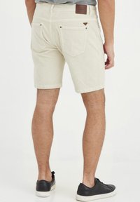 Beige cordfløyelsshorts med slim fit, to baklommer med knappdetaljer og et lærpatch på livet.