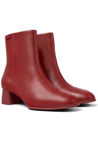 Par de botines de cuero rojo liso con puntas redondeadas y tacones bajos en un fondo blanco.