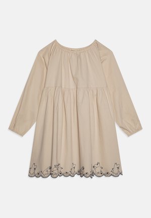 Beige kjole med lange ærmer, samlet talje og bølget kant, broderet med konturerede tegneseriefigurer af dyr og blomster.