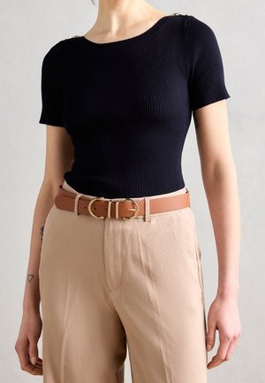 Granatowy prążkowany top z krótkim rękawem ozdobiony złotymi detalami, połączony z beżowymi spodniami i brązowym paskiem z podwójną klamrą.