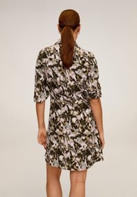 Das Kurzarmkleid hat ein blattgrünes und pinkes Blumenmuster, einen weichen Stoff, eine taillierte Taille und einen Hemdkragen.
