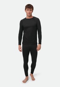 Top térmico negro de manga larga y leggings hechos de un material elástico, con un diseño ajustado y construcción sin costuras.