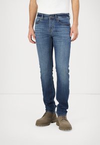 Men's blue denim jeans with a slim fit, featuring a classic five-pocket design, subtle fading, and a button-fly closure.