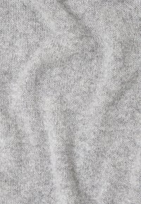 Tissu tricoté gris clair avec une surface douce et texturée. Le motif est uniforme, mettant en valeur un léger stretch et une finition lisse.