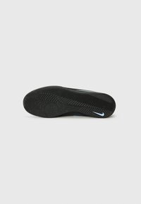 Nike sporta apavi ar teksturētu melnu gumijas zoli un zilu logo akcentu, kas paredzēti saķerei un izturībai.