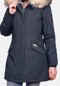 Mørkegrå parka med hætte foret med faux pels, lynlås lukning, to frontlommer og et mærke på ærmet. Holdbart stof, mellemlang design.