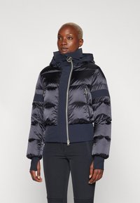 Donzen jacket in donker marineblauw, met een glanzende afwerking, cropped ontwerp, volledige rits, capuchon en elastische mouwen. Voorzien van horizontale stiksels.