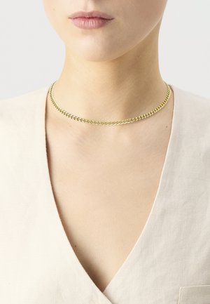 Collar choker de cadena color dorado con un diseño plano, que presenta eslabones entrelazados; exhibido sobre una prenda de tonos neutros.