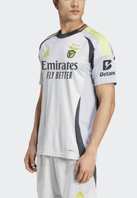 Hvid atletisk trøje med sorte og neongule accenter, logo og teksten "Emirates Fly Better". Åndbart stof med korte ærmer.