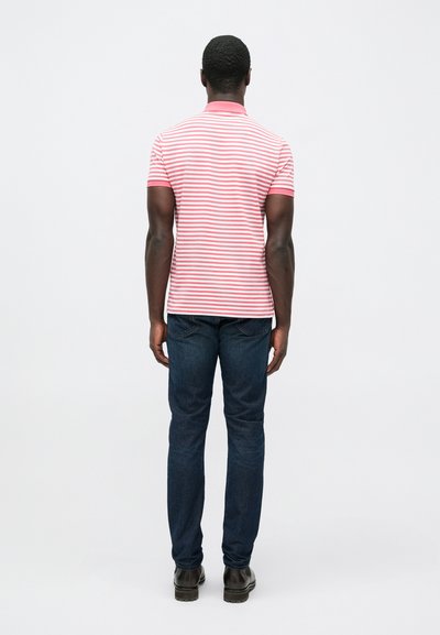 Červenobíle pruhované polokošile s límečkem, v kombinaci s tmavě modrými džínami a hnědými botami. Jednoduché pozadí, model otočený zády.