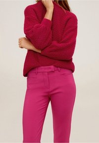 Sweter z fakturą dzianiny w kolorze fuksji z opuszczonymi ramionami, zestawiony z dopasowanymi spodniami w kolorze fuksji, posiadającymi płaski przód i kieszenie.