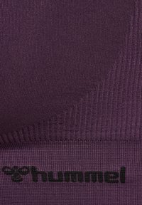 Fioletowy sportowy biustonosz z teksturowanym, prążkowanym wzorem o gładkim wykończeniu oraz czarnym logo u dołu. Brak widocznych ramiączek.