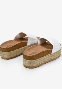 Sandalias de plataforma blancas tipo slip-on con una entresuela de corcho, base envoltura de yute y un parte superior sintética suave con dos correas anchas.