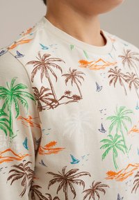 Krämfärgad sweatshirt med mönster av palmträd och segelbåtar i grönt, brunt, orange och blått. Mjuk tyg, rundad halsdesign, kortärmad.