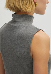 Graues ärmelloses Rollkragenoberteil aus geripptem Strickstoff, mit hohem Kragen und glatter Textur, von hinten gezeigt.
