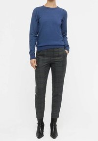 Blue knit sweater with a round neckline, paired with grey check-patterned trousers. Trousers taper at the ankle, worn with black ankle boots.