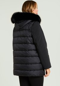 Sort boblejakke med aftagelig sort pelskrave. Har quiltet design, lange ærmer og løs pasform, egnet til koldt vejr.