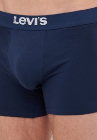 Boxeri scurți de culoare bleumarin, confecționați dintr-un material moale, având un logo alb contrastant "Levi's" pe banda de talie și o potrivire strânsă.