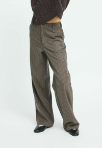 Pantalons marron à rayures avec une coupe droite, dotés d'une taille et de poches avant, en tissu léger.