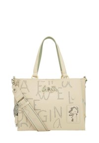 Bolso de mano color beige claro hecho de cuero sintético, con letras perforadas, una ilustración de personaje, dos asas y una correa desmontable.