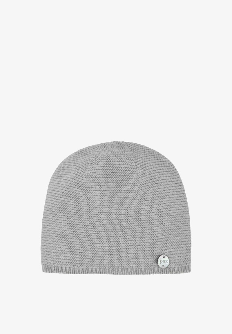 Bonnet tricoté gris avec un bord côtelé et une petite étiquette logo circulaire située en bas à droite. Texture lisse sur l'ensemble.