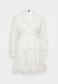 Witte bloemenjurk met lange mouwen, ruches en een gelaagd ontwerp. Voorzien van kleine blauwe en groene bloemenpatronen op een lichtgewicht stof.