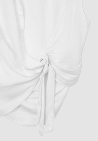 Top bianco senza maniche con un dettaglio di nodo sul bordo, realizzato in tessuto morbido e liscio, caratterizzato da una silhouette rilassata e drappeggiata.