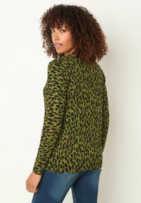 Langärmliges Oberteil mit grünem Leopardenmuster aus strukturiertem Stoff, mit schwarzen Flecken, rundem Halsausschnitt und lässiger Passform. Tragen mit Denim.
