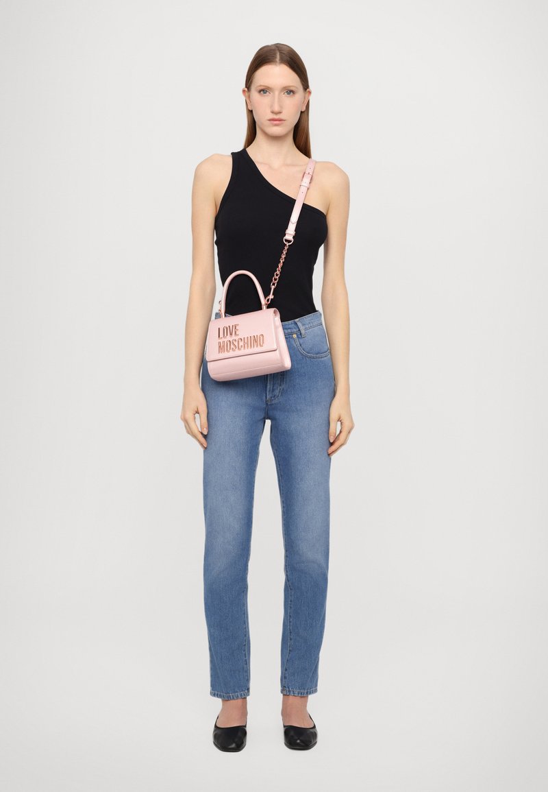 Bolsa de pele rosa com um design estruturado, apresentando uma alça superior, uma alça cruzada e o emblema "LOVE MOSCHINO" em relevo na parte frontal.