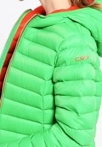 Zielona, puchowa kurtka z kapturem, posiadająca przeszywane sekcje i gładką fakturę. Logo CMP na rękawie. Kontrastowa czerwona podszewka wewnętrzna.