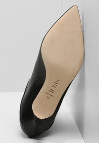 Chaussure à talon haut noire avec un bout pointu, en cuir lisse et une semelle beige. Présente un marquage sur la semelle. Taille 37.