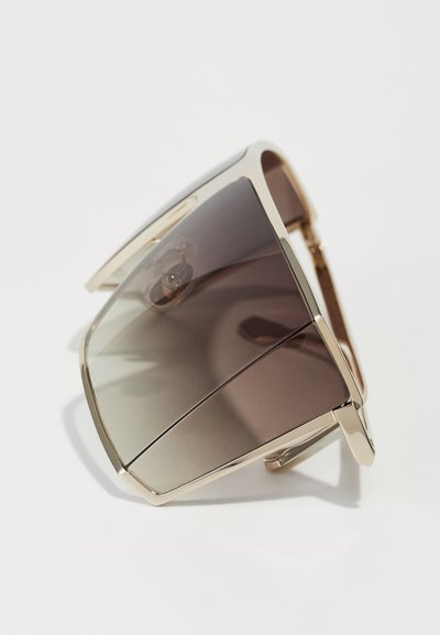 Lunettes de soleil avec une monture en métal doré, au design surdimensionné, lentilles dégradées marron et forme angulaire ; dotées d'un pont de nez pour un maintien sécurisé.