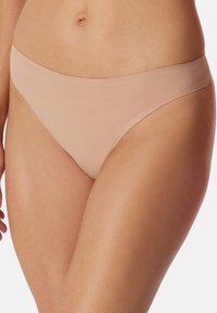 Beige g-streng trusser lavet af glat, strækbart stof. Lavtaljet design med minimal dækning og ingen synlige sømme eller pynt.