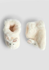 Furry cremétofflor med upphöjda kaninöron, blommiga accenter på öronen och tassarna, mjuk textur och ankelhögt design som erbjuder mysig täckning.
