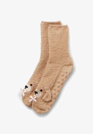 Calzini in pile color nocciola con design a faccia d'orso e dettagli neri, accompagnati da un fiocco rosa. Dotti antiscivolo testurizzati sulla suola per una maggiore sicurezza.