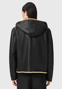 Schwarze Lederjacke mit Kapuze, ausgestattet mit einem weichen, hell gefärbten Futter am Kragen und Saum. Einfaches, zeitloses Design und regularer Schnitt.