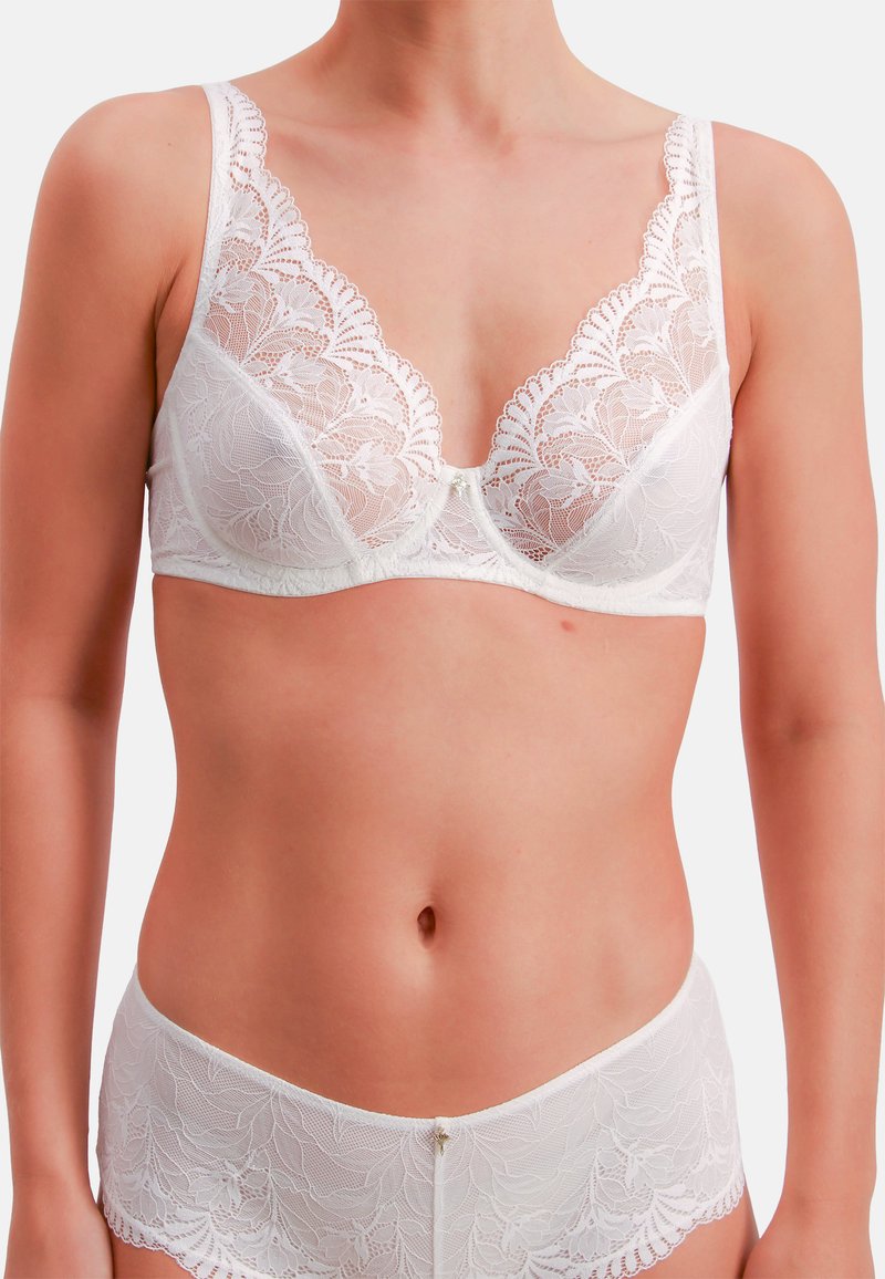 Witte kanten beha en bijpassende bikini-slip met gegolfde randen en bloemmotieven met subtiele glans. Zachte textuur en dunne bandjes.