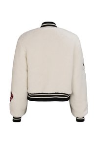 Biała, puszysta kurtka bomber z czarno-białym, prążkowanym kołnierzem i mankietami. Ozdobiona dekoracyjnymi naszywkami na rękawach.